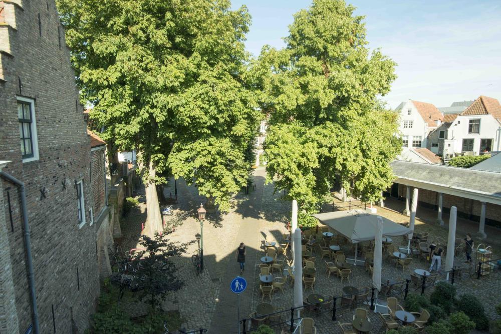 Uitzicht vanuit het logement op het terras onder de bomen op de Vismarkt
